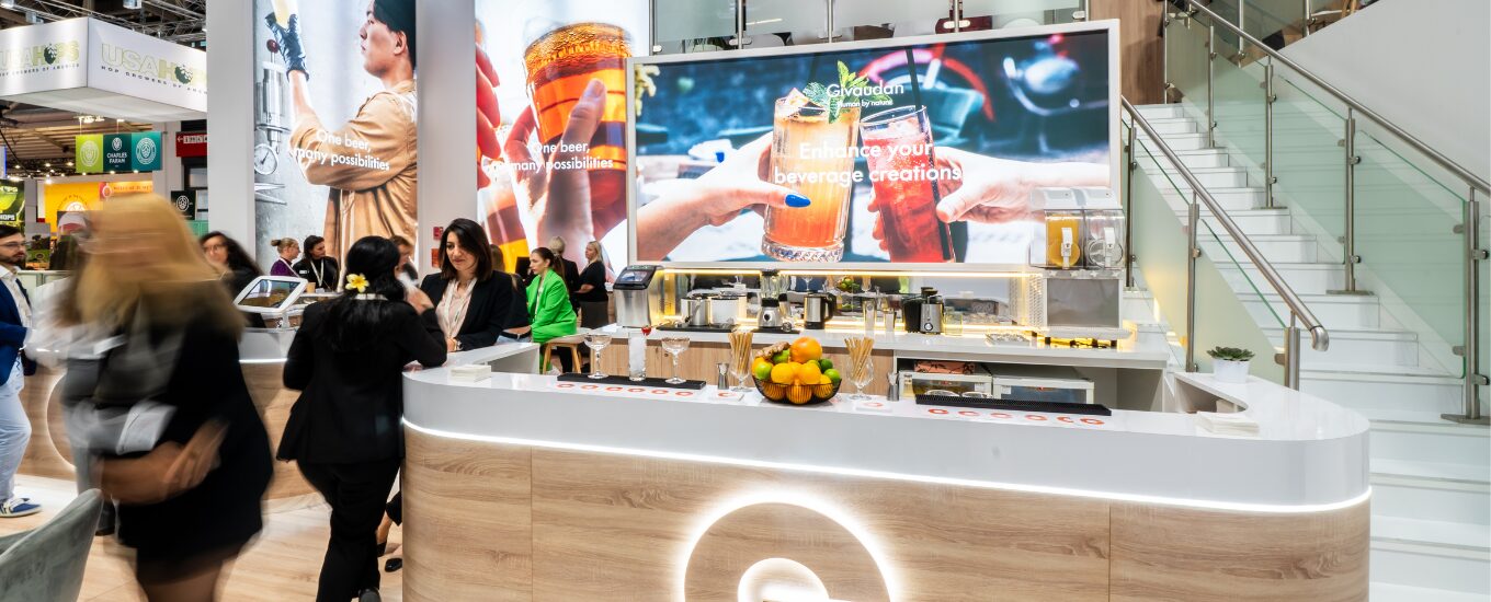 A Givaudan booth at drinktec 2025 front shot of the bar area with multiple people walking around and chatting